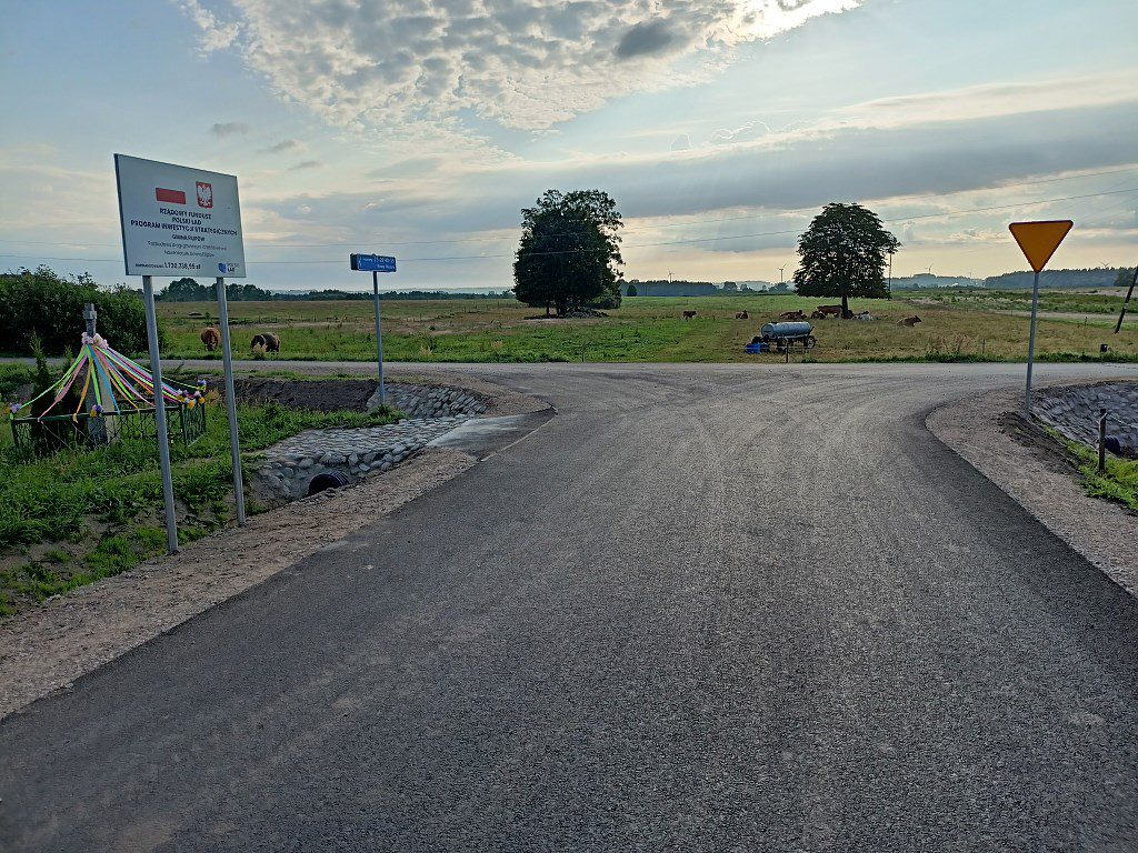 Nowa droga asfaltowa i tablica informacyjna o dofinansowaniu z Rządowego Funduszu Polski Ład w gminie Kurzętnik