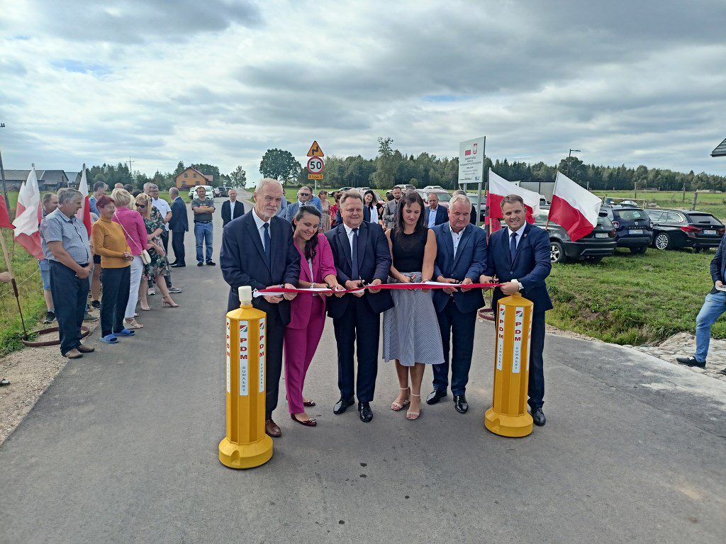 Przedstawiciele władz przecinają biało-czerwoną wstęgę podczas uroczystego otwarcia nowej drogi
