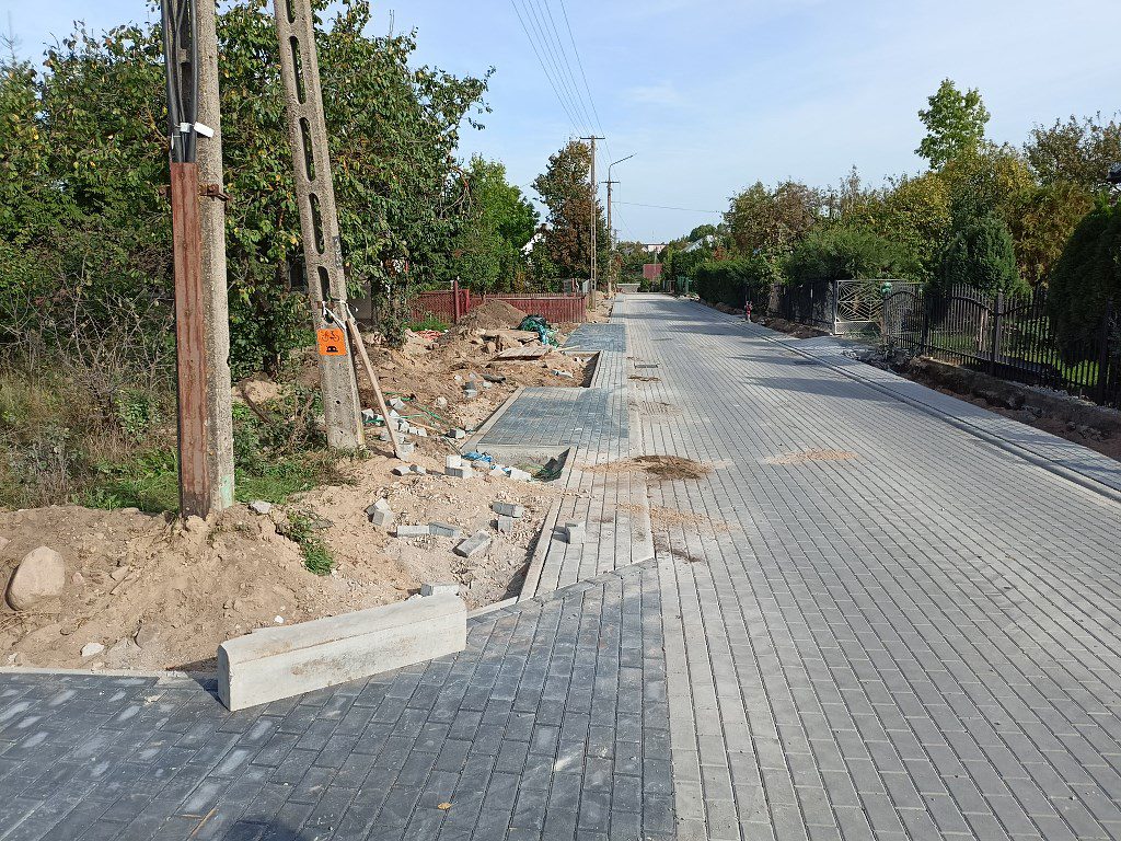 Remont drogi osiedlowej z nową nawierzchnią z kostki brukowej i trwającymi pracami przy chodniku